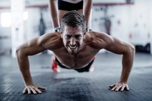 Man doing push-ups with woman kneeling on his back